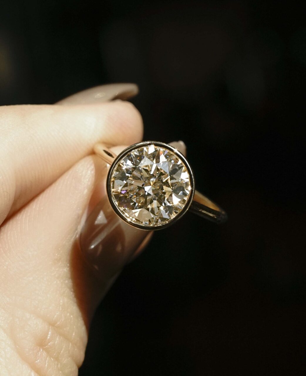 A round brilliant diamond cut  set in a two tone bezel ring 
