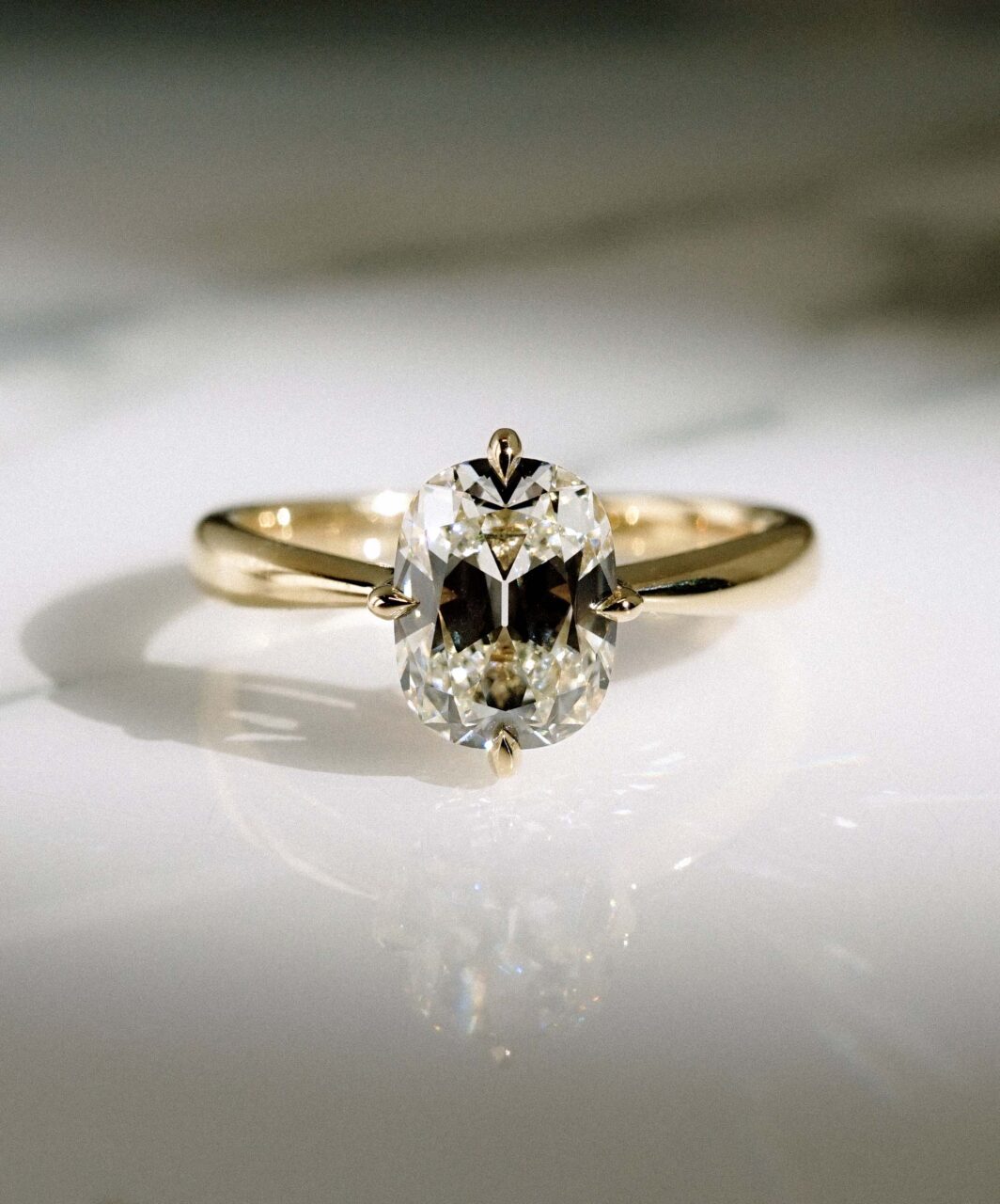 A compass prong oval diamond engagement ring with prominent bow-tie 