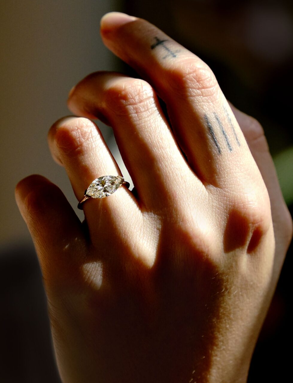 An east-west Marquise cut diamond is worn with a simple gold band 