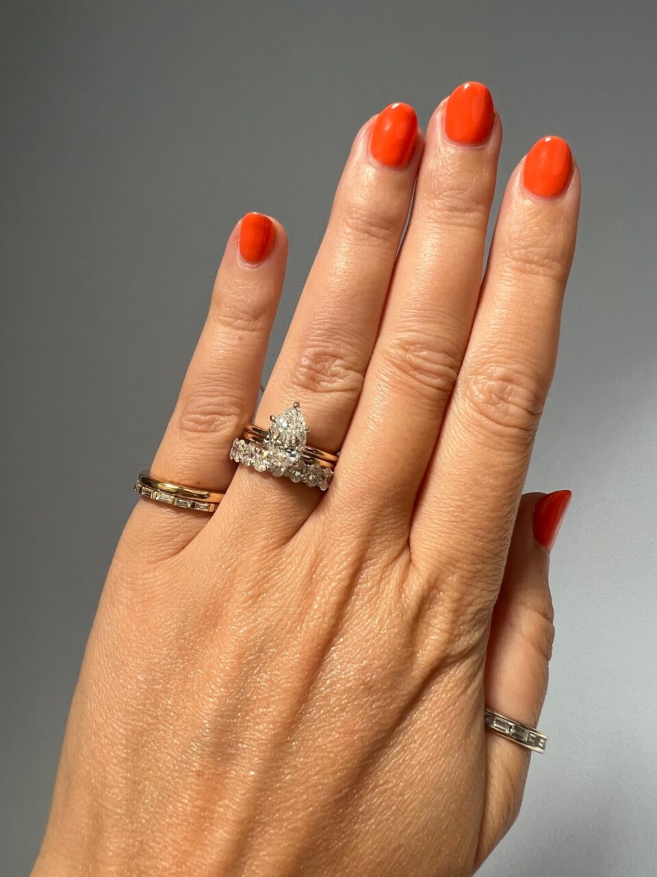 A Marquise solitaire engagement ring rests atop an oval eternity band. 