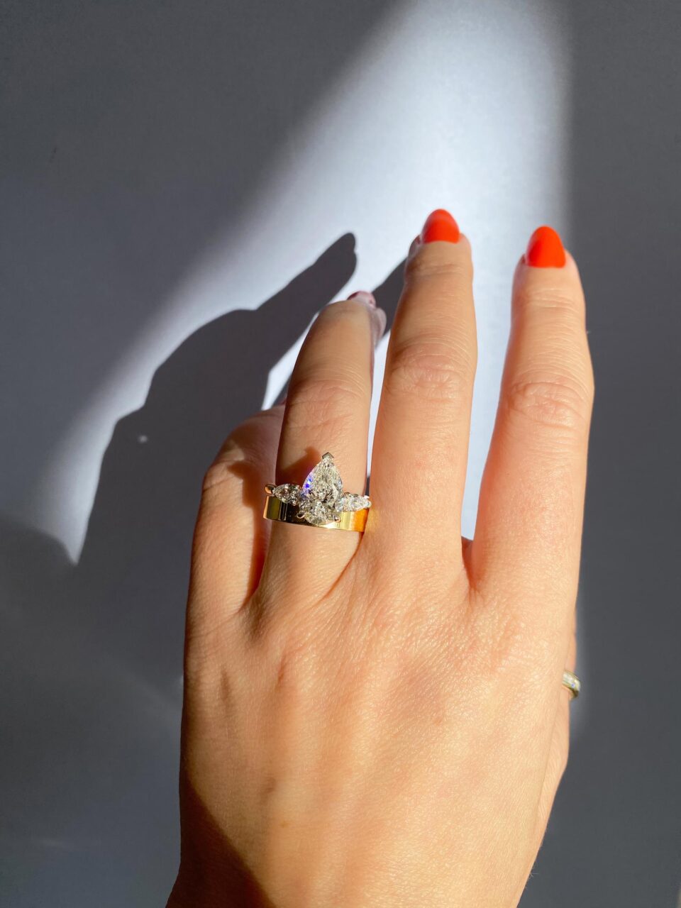 A pear shaped diamond stacked atop a thick wedding band 