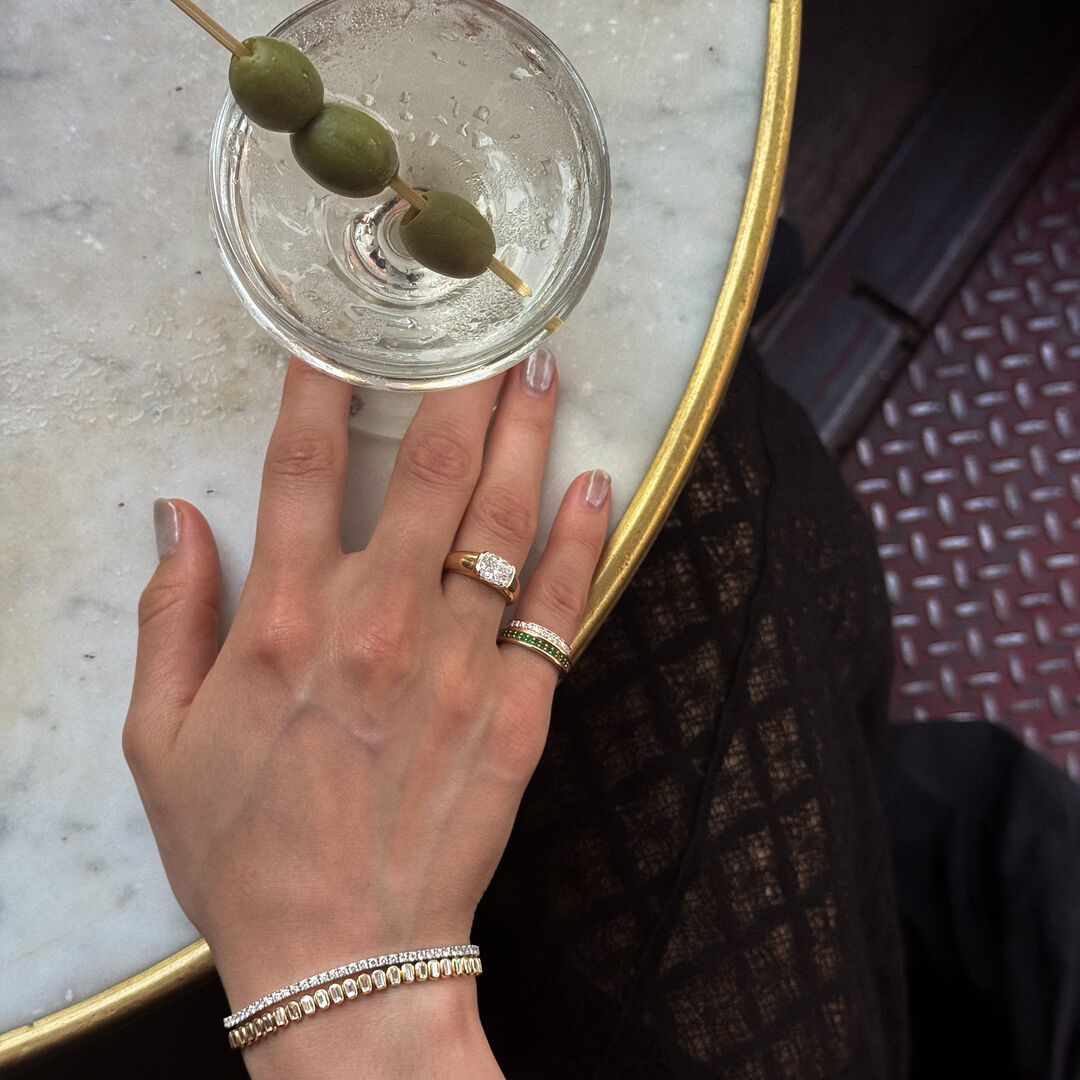 A woman holds a martini and wears a variety of lab grown diamond jewelry 